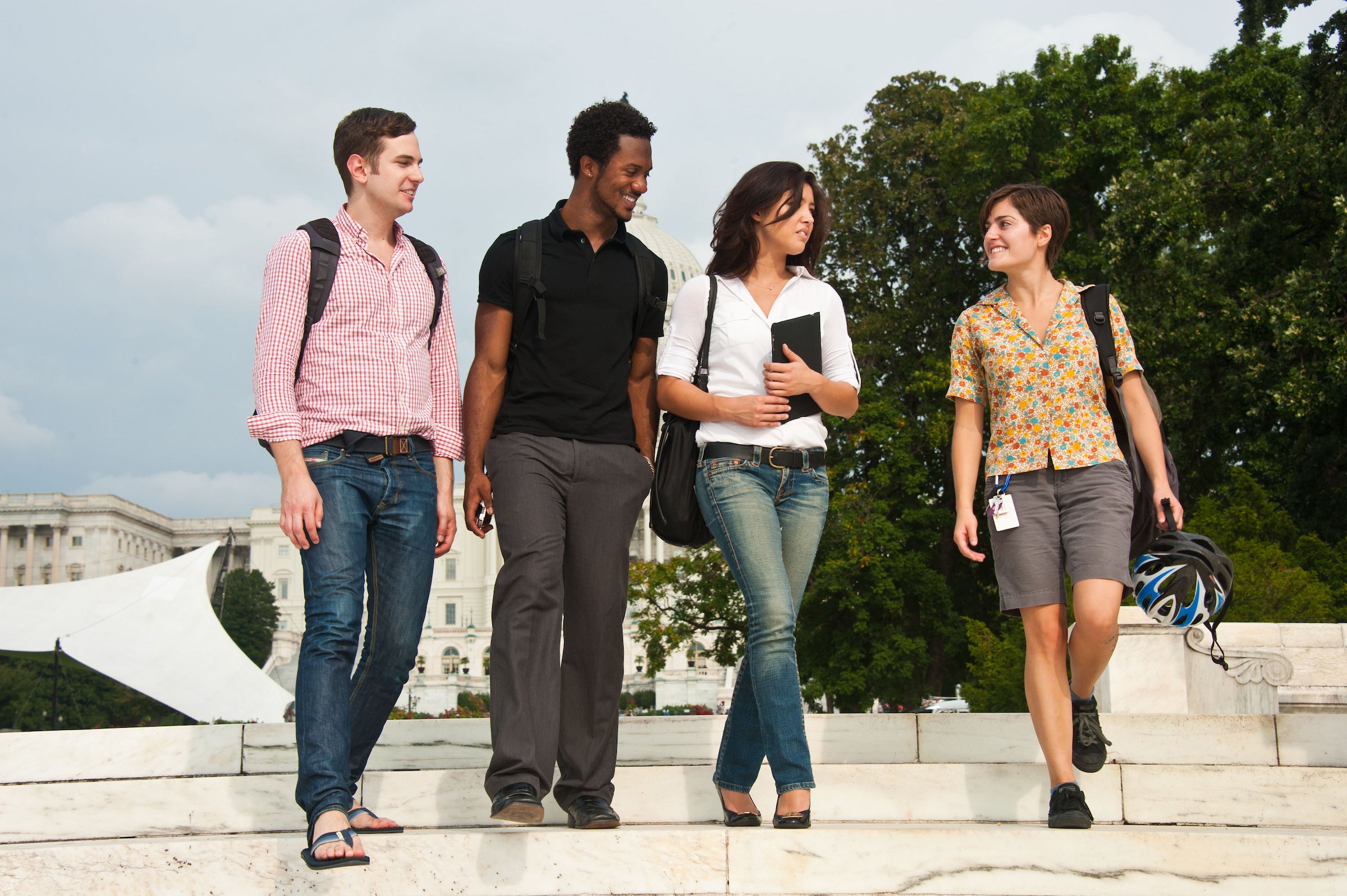 Four young people of mixed races and genders walk together down a set of stone stairs.