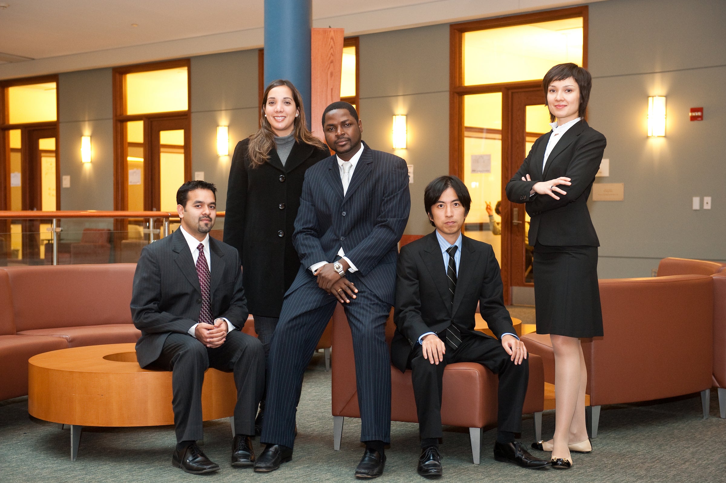 A group of 5 professional adults of mixed races and genders pose in an atrium.